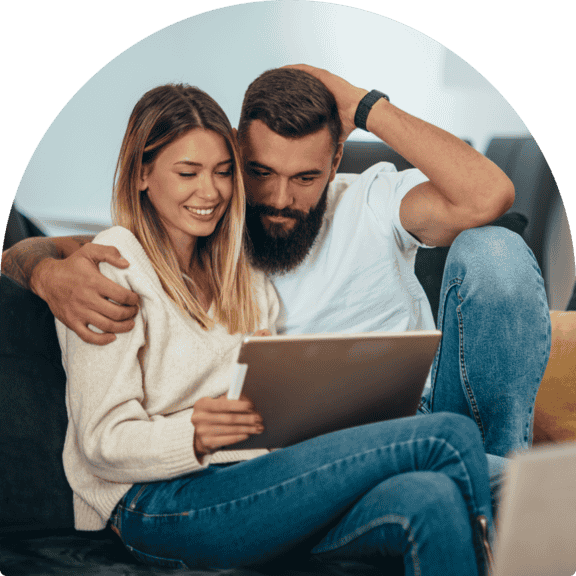 Couple sitting on couch together using tablet to explore insurance options